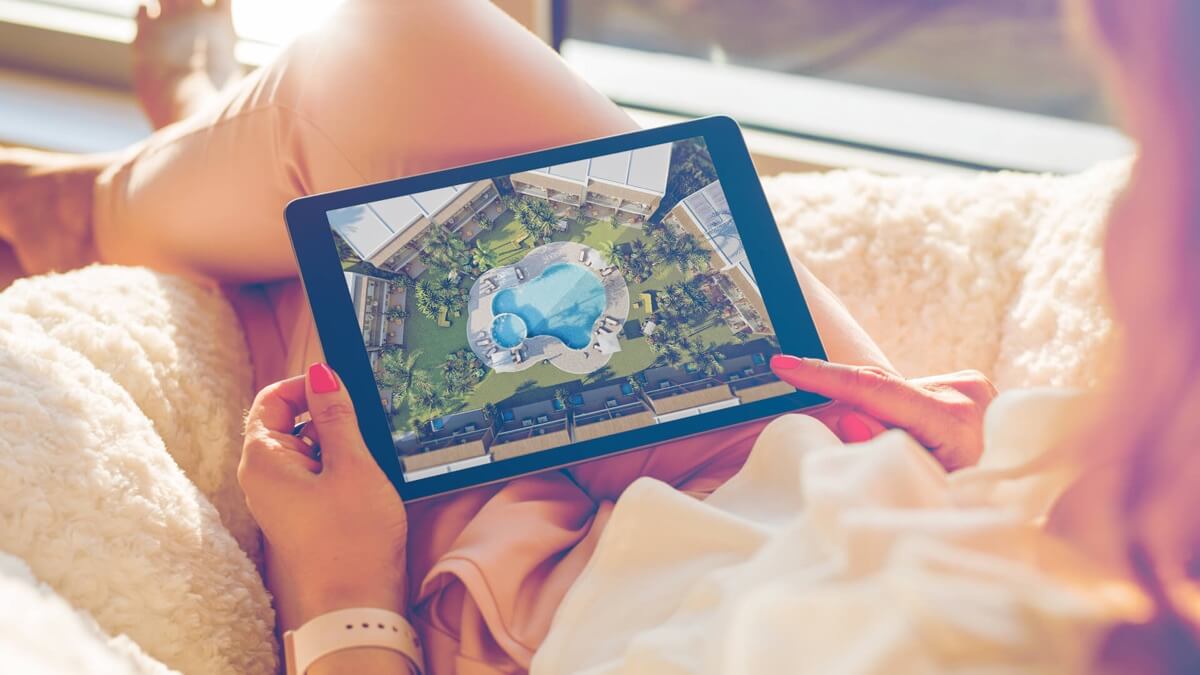 Cliente sfoglia su tablet il rendering 3D aereo di un resort con piscina — ADDING Studios
